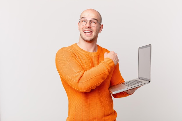 Glatzköpfiger Mann mit Computer, der sich glücklich, positiv und erfolgreich fühlt, motiviert, wenn er sich einer Herausforderung stellt oder gute Ergebnisse feiert