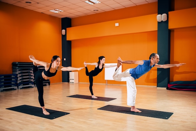 Gleichgewichtsübung, weibliche Yoga-Gruppe in Aktion, Training mit dem Ausbilder, Training im Fitnessstudio. Yogi drinnen