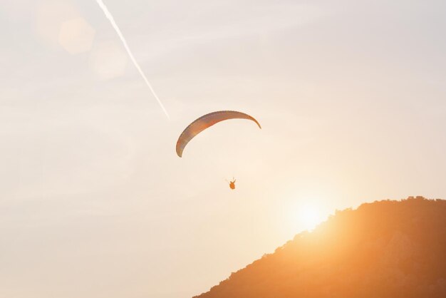 Gleitschirm am sonnigen Himmel mit einer Spur eines Flugzeugs