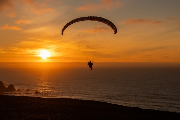 Gleitschirm fliegt über diese Küste bei Sonnenuntergang. Paragliding Sport