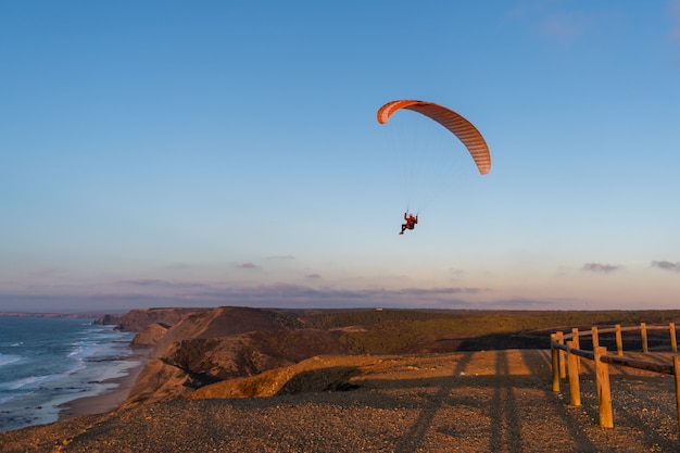 Gleitschirm fliegt über diese Küste bei Sonnenuntergang. Paragliding Sport