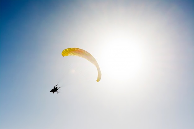 Gleitschirmfliegen mit Paramotor auf blauem Himmel