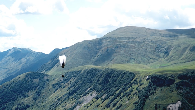 Gleitschirmfliegen über Berge während des Sommertages - Georgia, Kazbegi