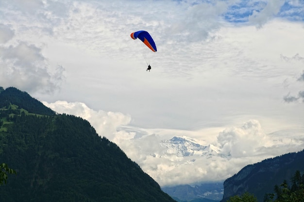 Gleitschirmfliegen über einer alpinen Landschaft mit einem schneebedeckten Berg