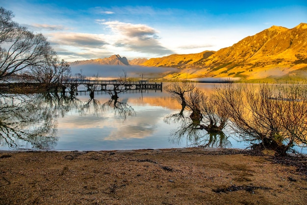 Glenorchy bei Sonnenaufgang, wenn die goldene Morgensonne die Berge wärmt und die Berge und Weiden sich auf dem Lake Wakatipu spiegeln