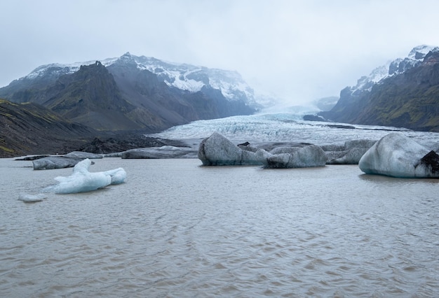 Gletscherzungenrutsche von der Vatnajokull-Eiskappe oder dem Vatna-Gletscher in der Nähe des subglazialen Oraefajokull-Vulkans Island Gletscherlagune mit Eisblöcken und umliegenden Bergen