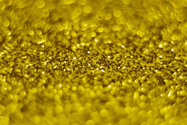 Glitzerspritzer und Linseneffekt auf goldglänzendem trendigem Hintergrund. Pailletten. Festlicher Hintergrund für Ihre Projekte. Verschwommene goldene festliche Bokeh-Lichter. Weihnachtsfestzeitkonzept auf Hintergrund.