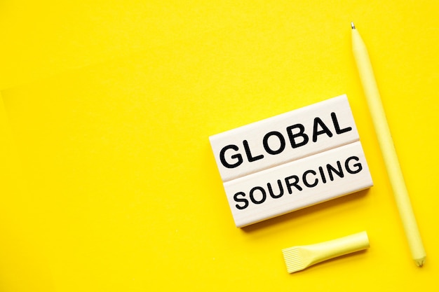 GLOBAL SOURCING. HOLZSTANGEN mit Informationen auf dem Desktop mit gelbem Hintergrund.