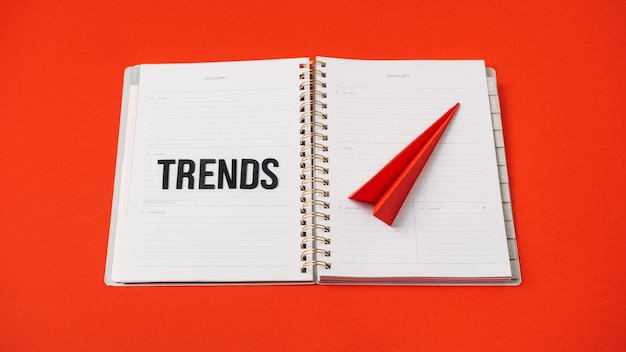 Globale Welttrends Top neue Trends prognostizieren Worttrends und rotes Papierflugzeug auf rotem Hintergrund