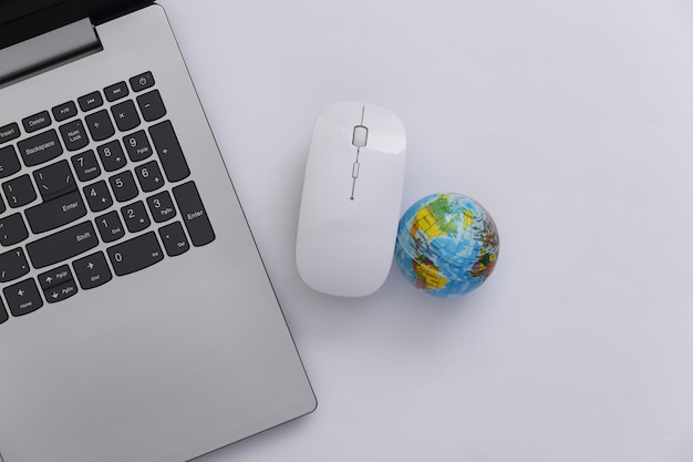 Globales Netzwerk. Laptop mit PC-Maus und Globus auf weißem Hintergrund. Onlinegeschäft. Ansicht von oben. Flach legen