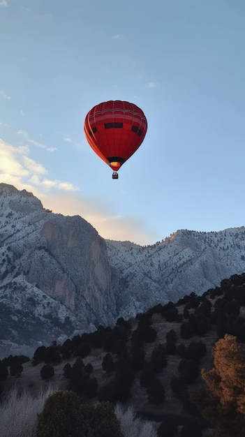 Un globo aerostático rojo vuela sobre una cadena montañosa.