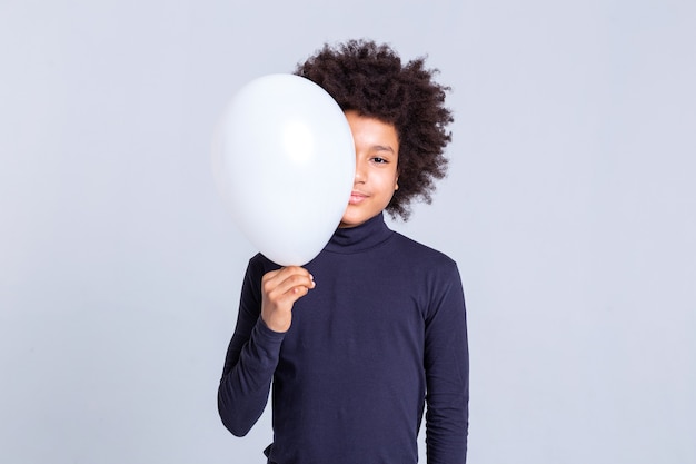 Globo de aire blanco. Bastante joven con peinado afro que cierra la mitad de su rostro con un globo mientras usa cuello alto azul