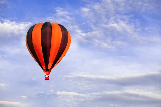 Globo de aire caliente rojo volando sobre el cielo azul