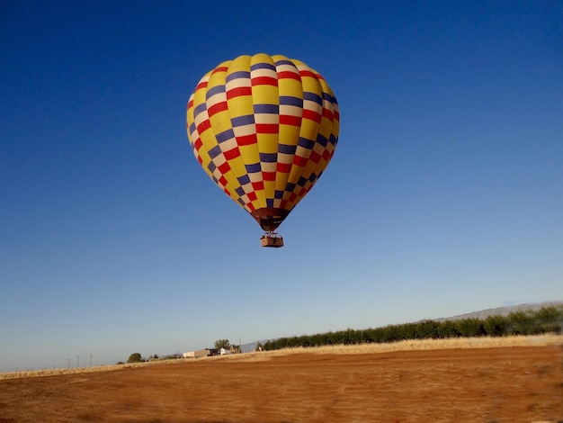 globo de aire caliente volando sobre la tierra contra un cielo azul despejado