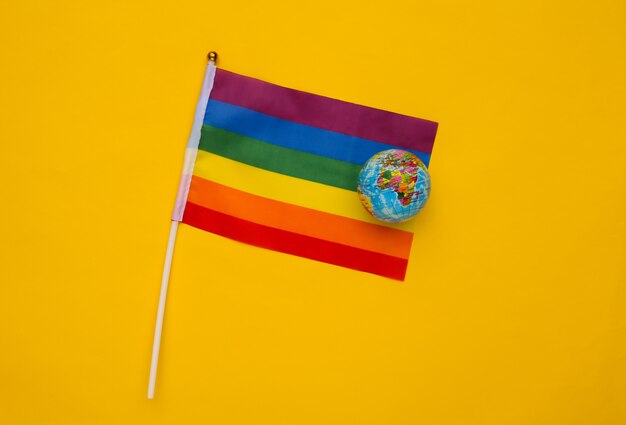 Globo y bandera arco iris LGBT sobre fondo amarillo. Desfile gay, libertad, tolerancia