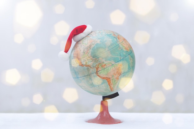 Globo com chapéu de natal na neve bokeh flare Chapéu de Papai Noel como conceito de viagem