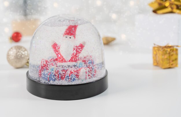 Foto globo de neve com papai noel e caixas de presentes foco seletivo e luzes bokeh composição de inverno