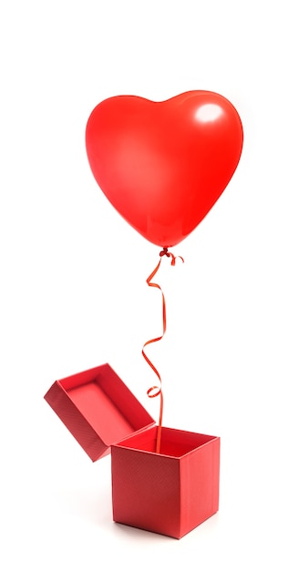 Un globo en forma de corazón sale volando de una caja de regalo abierta. Caja y globo aislado sobre fondo blanco. Regalo de San Valentín.