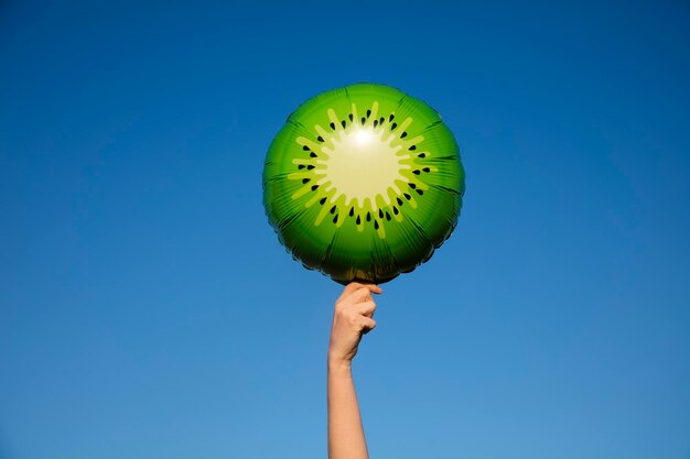 Globo de kiwi de verano sostenido en el aire contra un cielo azul brillante de verano