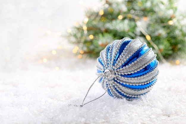 Globo de Navidad plateado y azul sobre una mesa cubierta de nieve