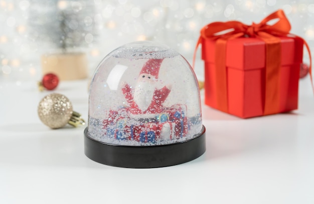 Globo de nieve con Santa Claus y caja de regalo roja Enfoque selectivo y luces Bokeh Composición de invierno