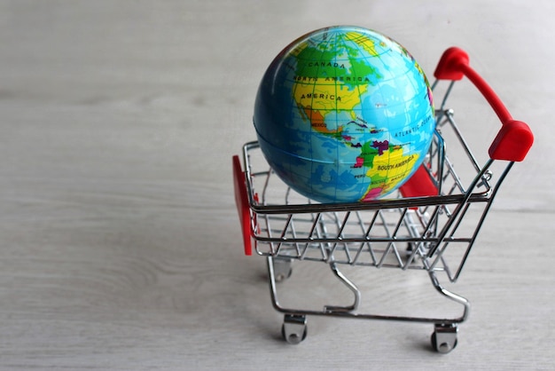 Globo del planeta tierra en carrito de compras de supermercado. Copiar espacio para texto