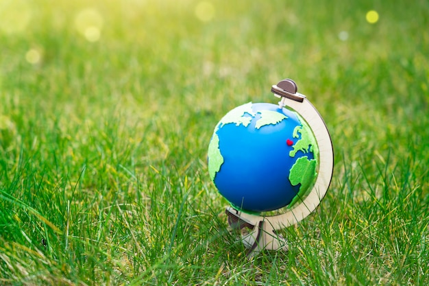 Globo del planeta Tierra de pie sobre la hierba verde en un día soleado en primavera o verano, símbolo ecológico, corazón rojo y mapa verde en globo azul sobre césped en el jardín