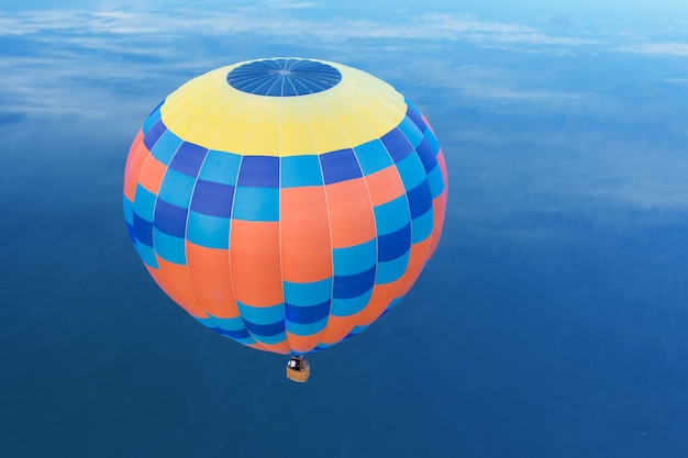 Globo sobre el lago, vista desde el dron. Globo amarillo y azul sobre un fondo de amanecer.