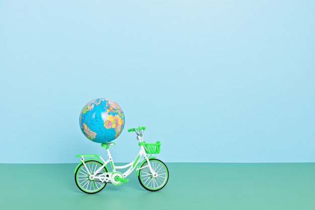 Globo terráqueo montando bicicleta verde sobre fondo azul. Día sin coches, día mundial de la bicicleta, protección del medio ambiente, concepto de estilo de vida sostenible con espacio de copia