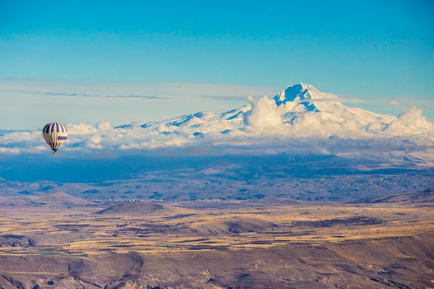 Globos de aire caliente en el aire sobre el Parque Nacional de Goreme con vistas nevadas al Monte Erciyes, Cappadocia, Tur