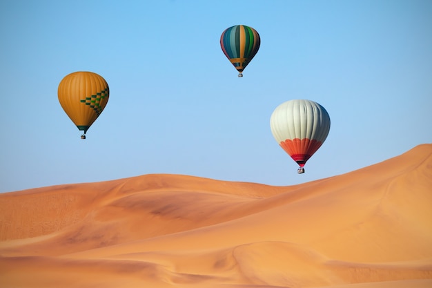 Globos de aire caliente de colores volando sobre las dunas de arena al atardecer. África, Namibia