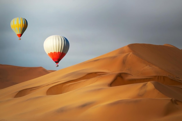 Globos de aire caliente de colores volando sobre las dunas de arena al atardecer