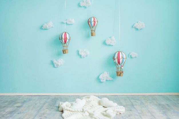 Globos de aire caliente de juguete y nubes en una pared azul