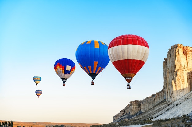 Globos de aire coloridos volando en el cielo despejado cerca de la enorme montaña blanca