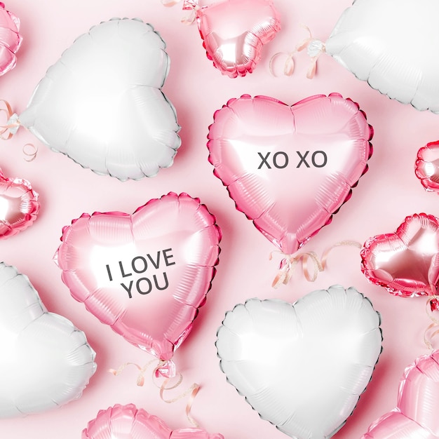 Globos de aire de papel de aluminio en forma de corazón sobre fondo rosa pastel. Concepto de amor. Celebración navideña. Decoración de San Valentín o boda / despedida de soltera. Globo metalico