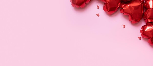 Globos de aluminio con forma de corazón rojo sobre fondo rosa Fondo del día de San Valentín con espacio de copia