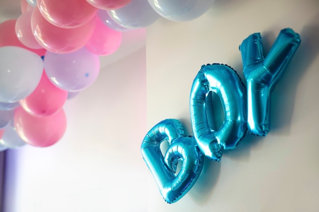 Globos azules y rosados del partido revelan el género en la sala de estar en la definición de la pared blanca de un niño o una niña