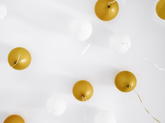 Globos blancos y dorados de vacaciones colgando cerca de la vela, fiesta de cumpleaños en casa, fondo festivo