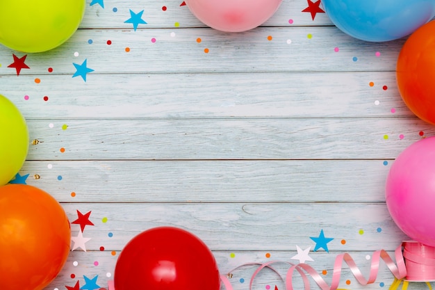 Globos de colores y confeti en la vista superior de la mesa de madera. Fondo festivo o de fiesta. Estilo plano. Carnaval.