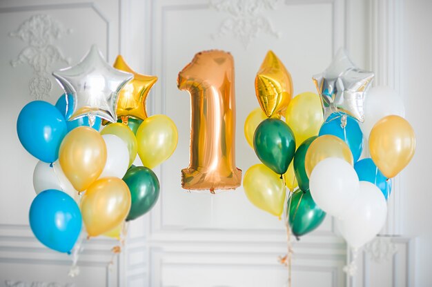 Globos de colores y lámina de oro grande número uno en una habitación blanca