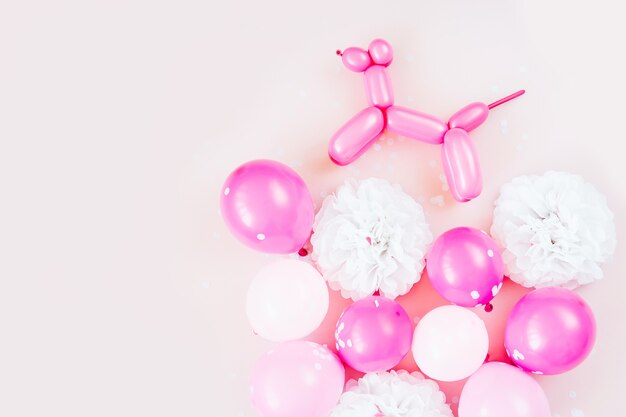 Globos de colores y perros globo sobre fondo rosa pastel. Concepto de fiesta festiva o de cumpleaños. Vista plana endecha, superior.