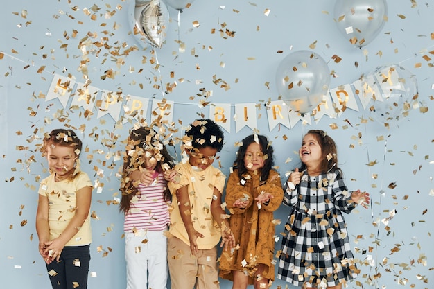 Globos y confeti Los niños que celebran la fiesta de cumpleaños en el interior se divierten juntos