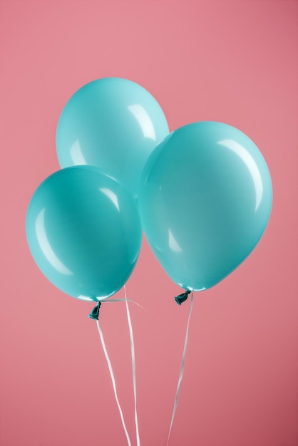 Globos festivos decorativos azules brillantes sobre fondo rosa