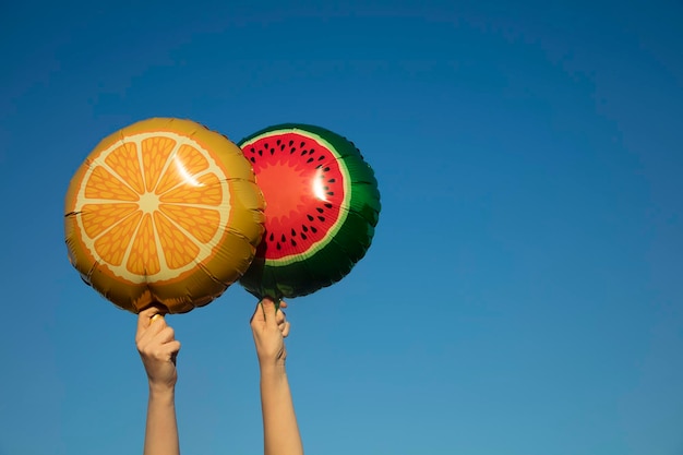 Globos de frutas de verano sostenidos en el aire contra un cielo azul brillante de verano