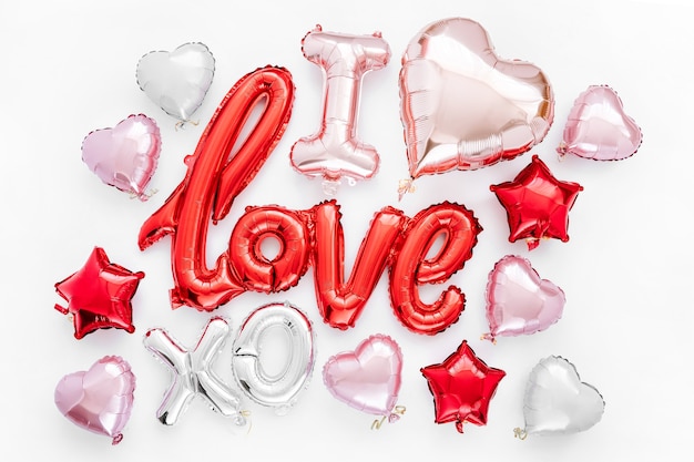 Globos de papel de color rojo y rosa en la forma de la palabra "Amor" con corazones sobre fondo blanco. Concepto de amor. Fiesta, celebración. Decoración de San Valentín o boda / despedida de soltera.
