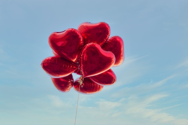 Globos rojos en forma de corazón con cielo azul en estilo vintage, concepto de amor y San Valentín. El amor está en el aire