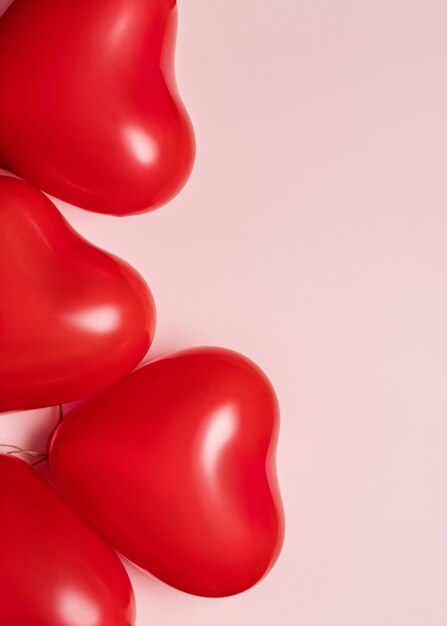 Globos rojos en forma de corazón sobre fondo rosa pálido. Concepto de día de San Valentín.