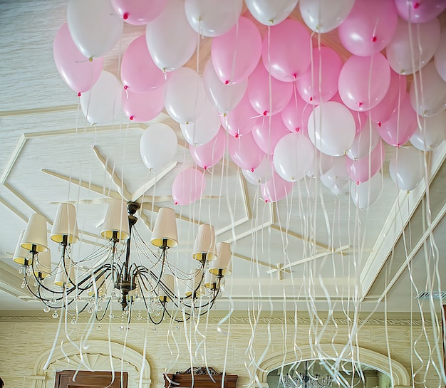 Globos rosas y blancos flotando en la habitación.