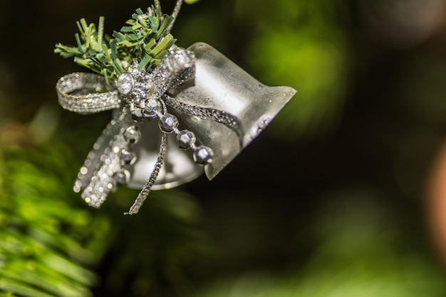 Glockenglas, das an einem Weihnachtsbaum mit grünem Hintergrunddetail hängt