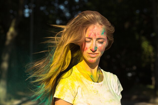 Gloriosa mujer rubia con cabello volador celebrando el festival de Holi